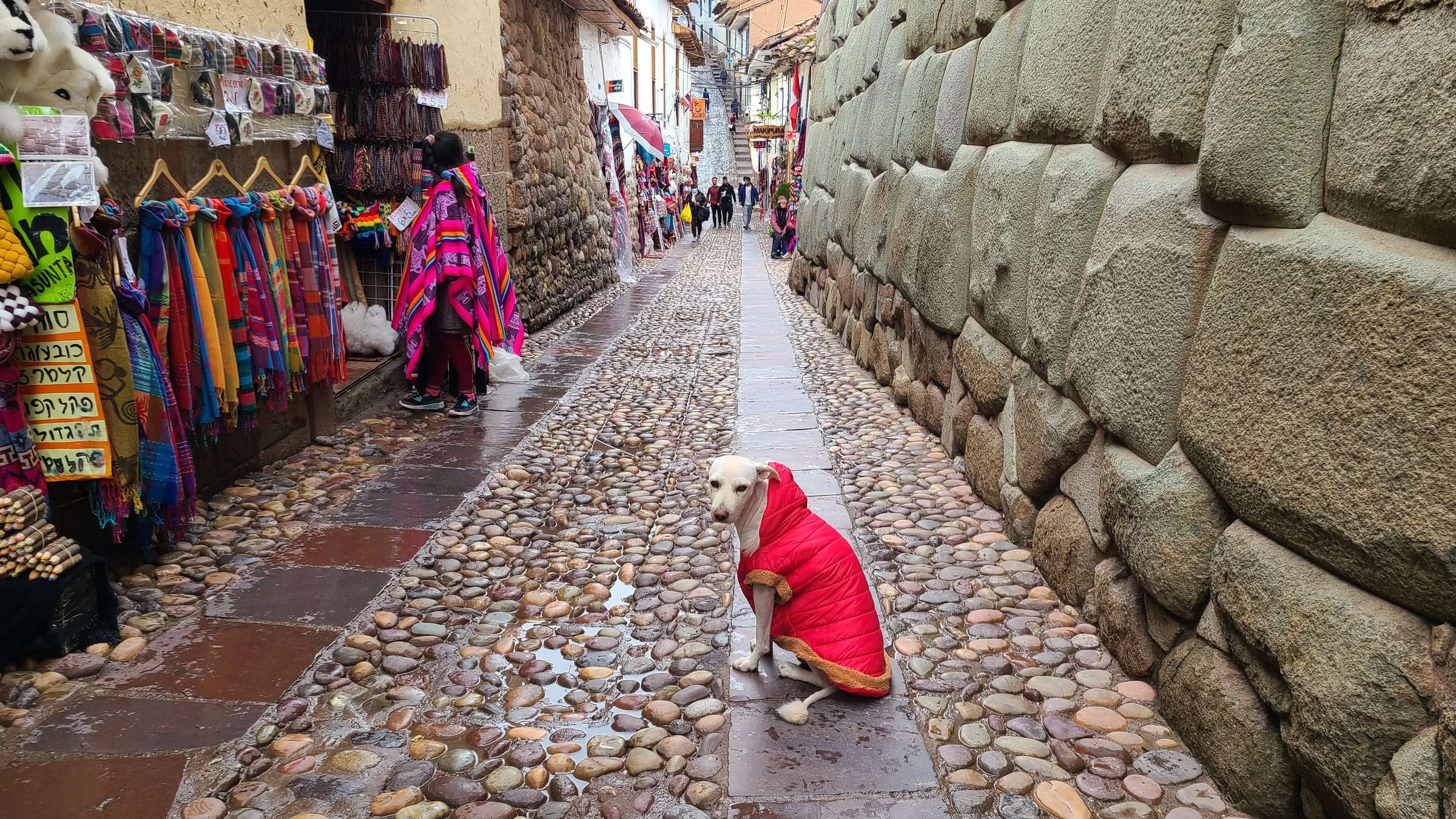 Inca stone wall street in Cusco with colorful textiles and cobblestone walkway