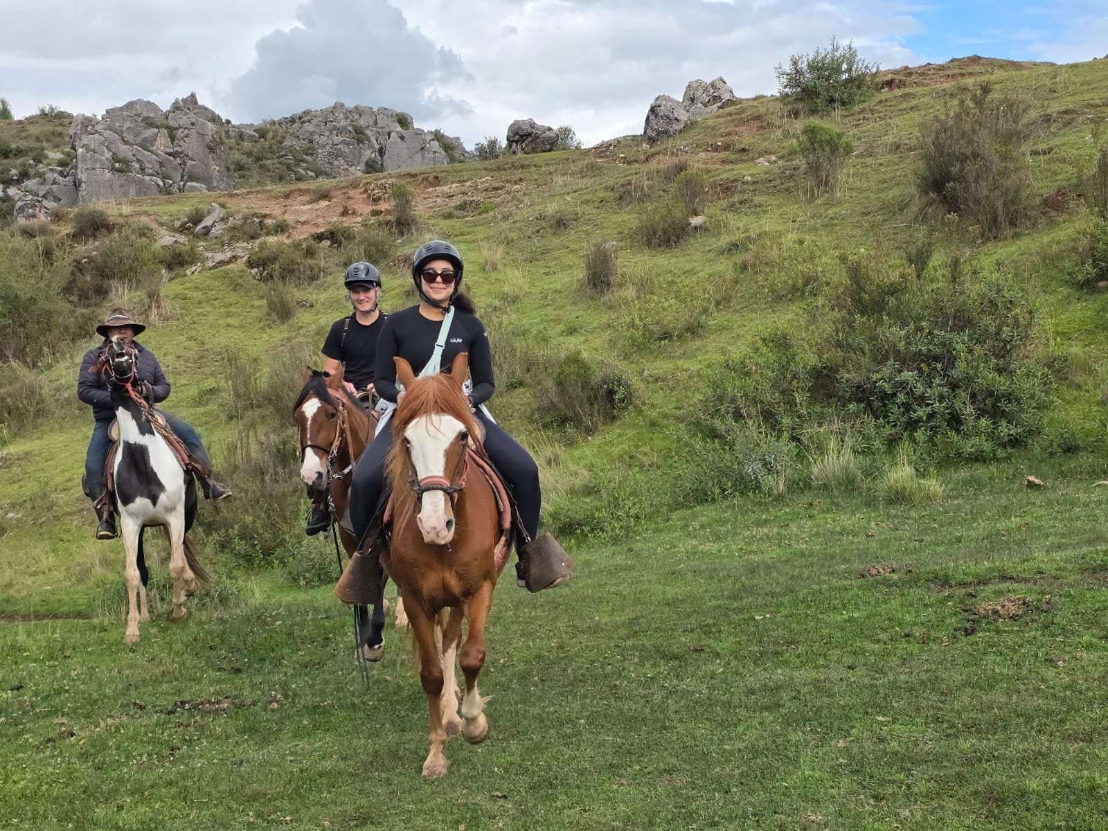Horseback riding group on green hills near Cusco Peru