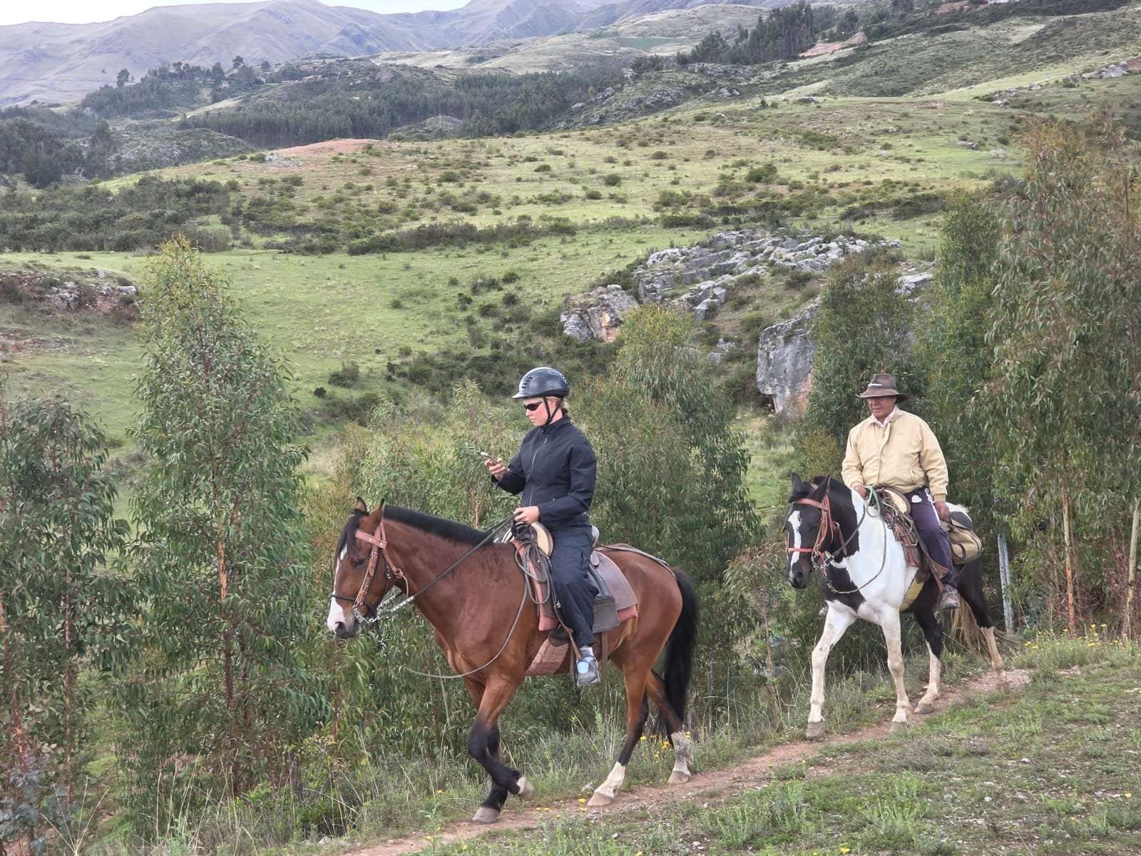 Two horseback riders through valley landscape near Cusco