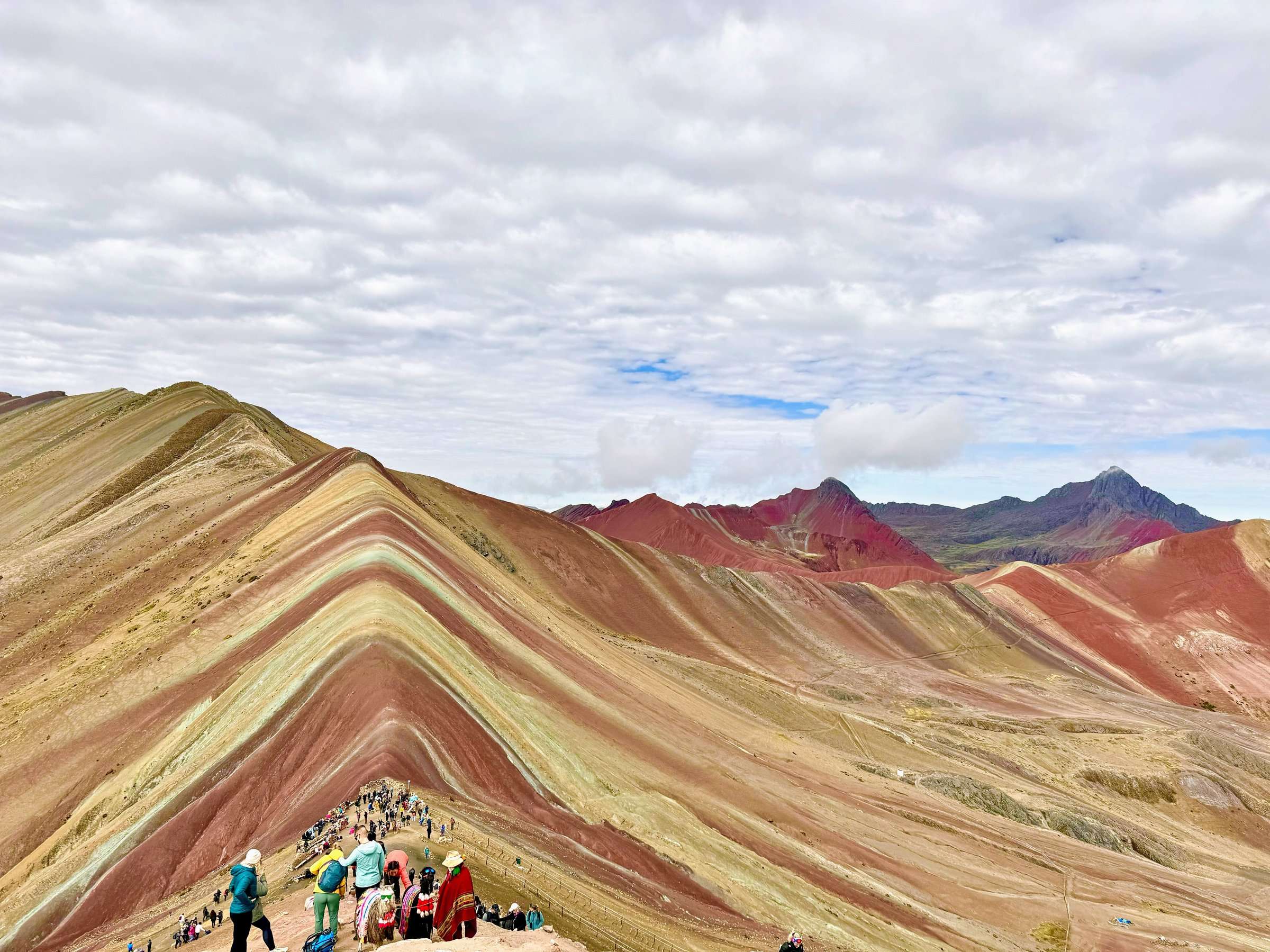 Wide landscape view of Palcoyo Rainbow Mountain and surrounding Andes
