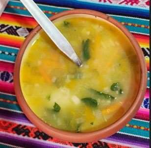 A clay bowl of traditional Andean vegetable soup served alongside the pachamanca feast